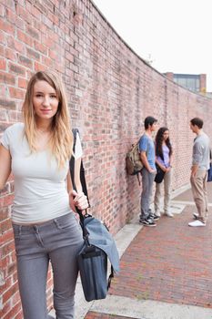 Portrait of a beautiful student posing while her friends are talking outside a building