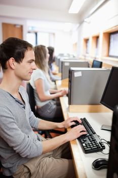 Portrait of a serious male student working with a computer in an IT room