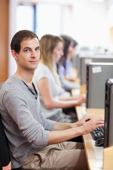 Portrait of a male student posing with a computer in an IT room