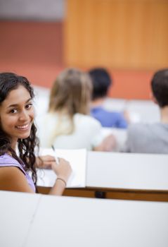 Portrait of a cute student being distracted in an amphitheater