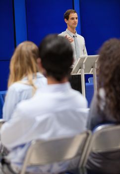 Portrait of a young man doing a presentation to business people