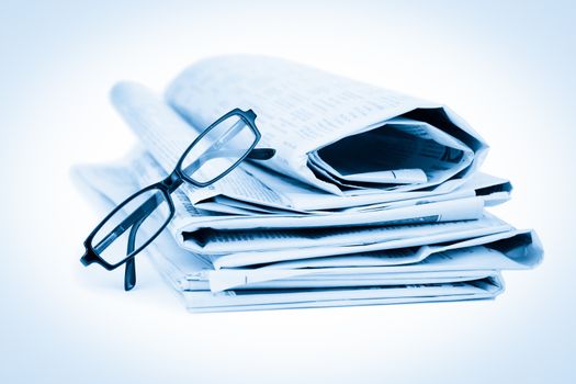 Newspapers and black glasses against a white a background