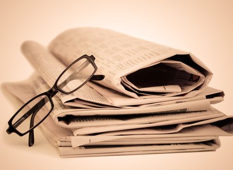 Newspapers and black glasses against a sepia a background