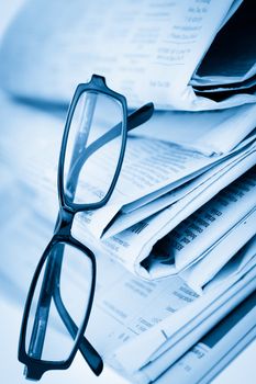 Newspapers and black glasses against a white a background