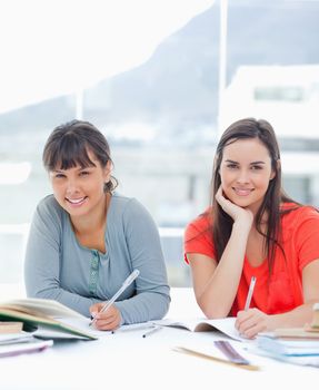 A pair of smiling women at a table as they work on homework together
