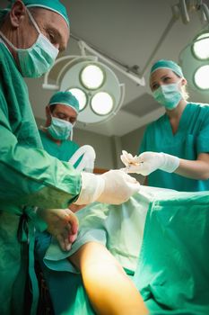 Team of surgeons operating the arm of a patient in a surgical room