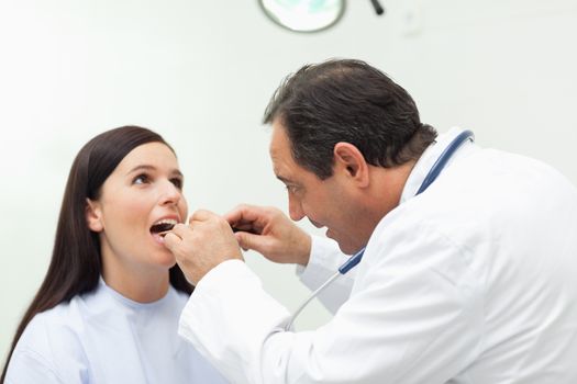 Doctor looking at the mouth of his patient in an examination room