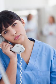 Nurse looking at camera while holding a phone in hospital ward