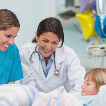 Doctor and nurse smiling to a child in hospital ward