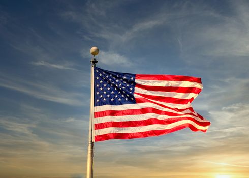 An American flag blowing in the wind over a blue sky