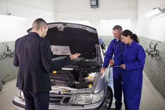 Client looking at a car engine in a garage