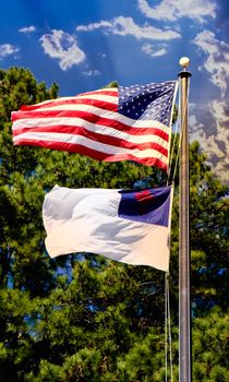 The Christian and American flags flying together against a background of trees and blue sky