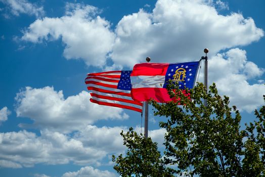 Flags of America and state of Georgia waving in the wind on a partly cloudy day