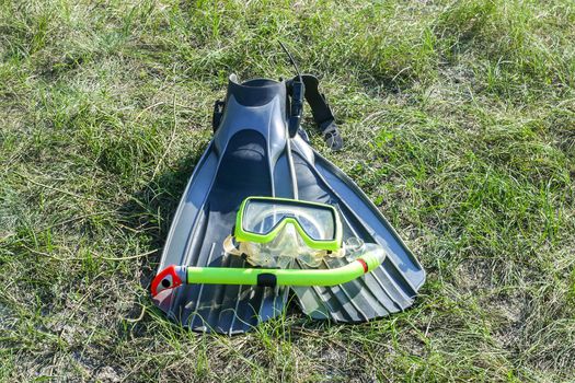 underwater mask, snorkel, and flippers lying on the grass. diver equipment