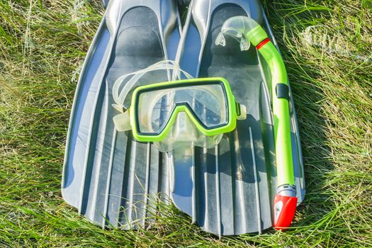 underwater mask, snorkel, and flippers lying on the grass. diver equipment