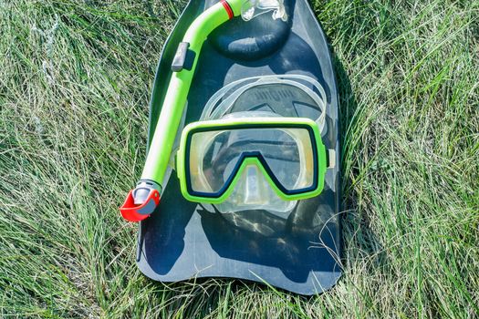 underwater mask, snorkel, and flippers lying on the grass. diver equipment