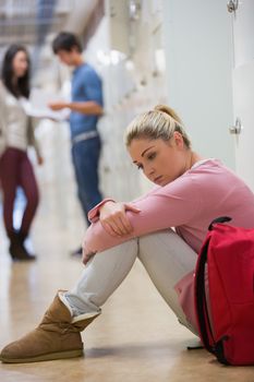 Students sitting on the floor at the hallway looking disappointed