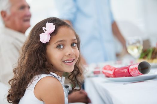Little girl sitting at table for christmas dinner and looking at camera