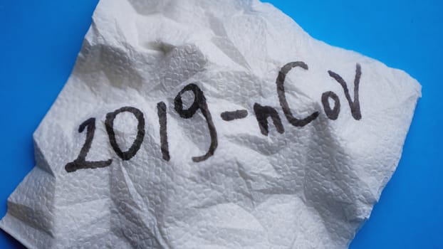 Crumpled napkin with 2019-nCoV virus on blue background. Victory over coronavirus
