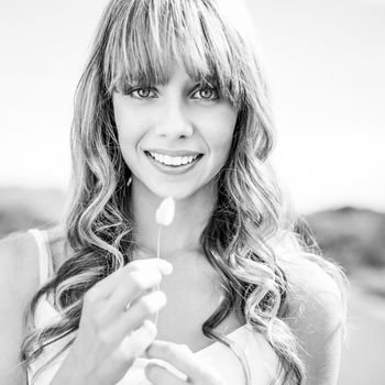 Black and white photograph of cheerful sexy blonde holding leaf