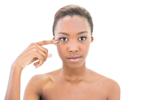 Peaceful natural beauty pointing at wrinkle on her eye on white background
