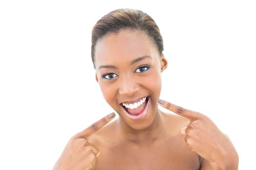 Smiling natural beauty pointing at her smile on white background
