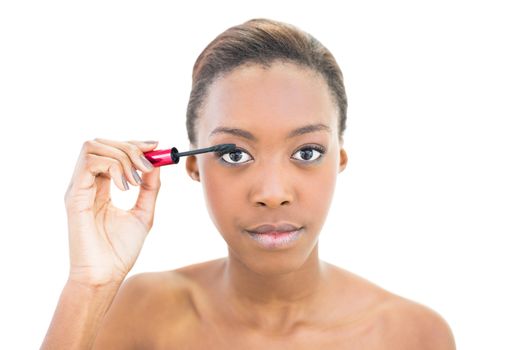 Natural beauty applying mascara while posing on white background