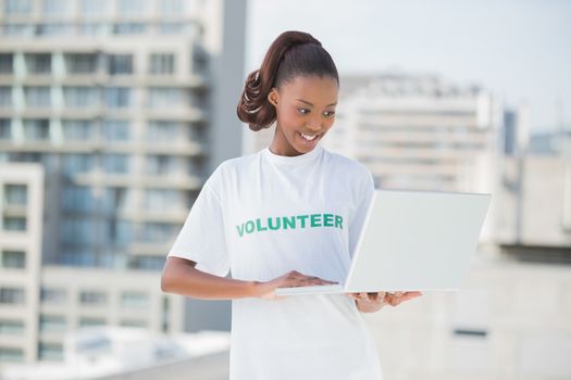 Happy volunteer using laptop outdoors on urban background 