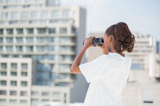 Volunteer woman using binoculars outdoors on urban background