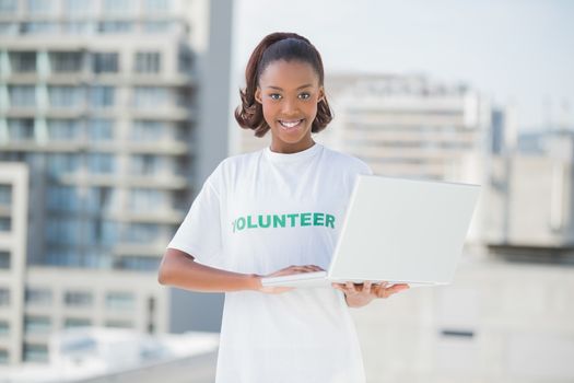 Cheerful volunteer smiling at camera outdoors on urban background