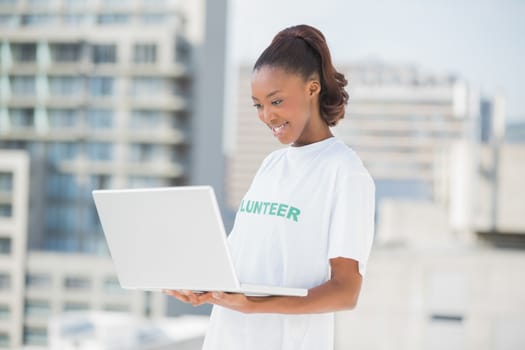 Smiling woman looking at her laptop outdoors on urban background