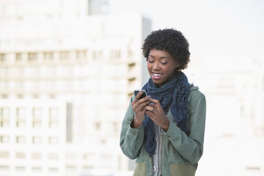 Cheerful casual model texting outdoors on a sunny day