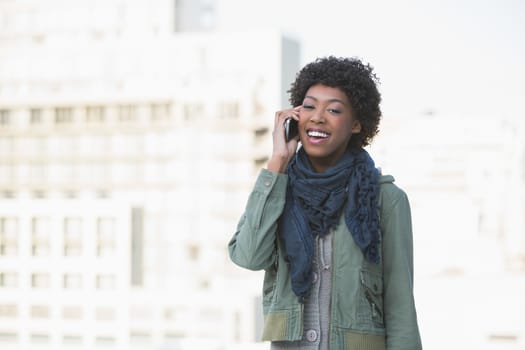 Smiling casual model on the phone outdoors on a sunny day