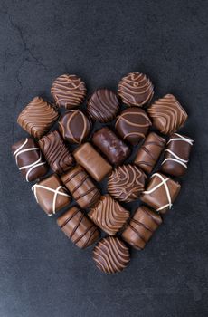 Stack of Chocolate candy in the shape of heart on a black background.