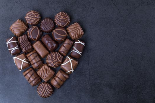 Stack of Chocolate candy in the shape of heart on a black background.  Focus on chocolate.