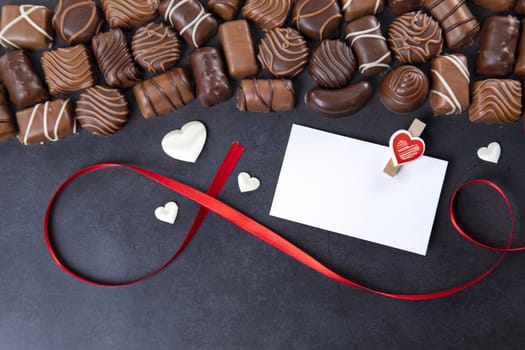 Chocolate pralines with white card for Valentines day on black background