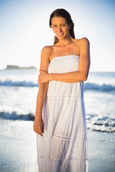 Calm woman in white summer dress posing on the beach