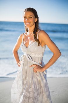 Smiling attractive woman in summer dress posing on the beach at dusk 