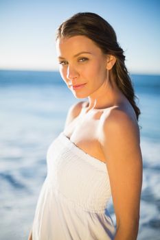 Peaceful brunette in white summer dress posing on the beach at dusk