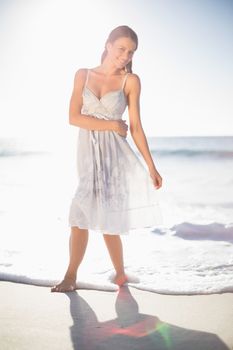 Smiling model in summer dress posing on the beach at dusk