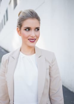 Smiling attractive businesswoman posing outdoors on urban background