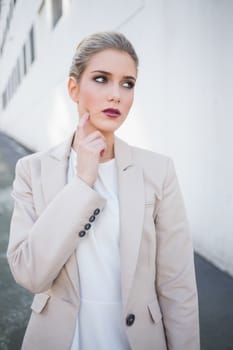 Thoughtful attractive businesswoman posing outdoors on urban background