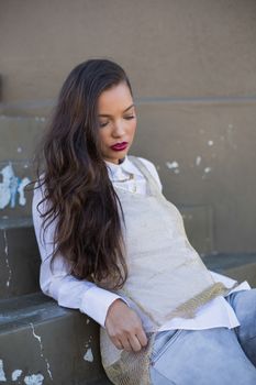 Glamorous pretty woman leaning on stairs outdoors on a bright day