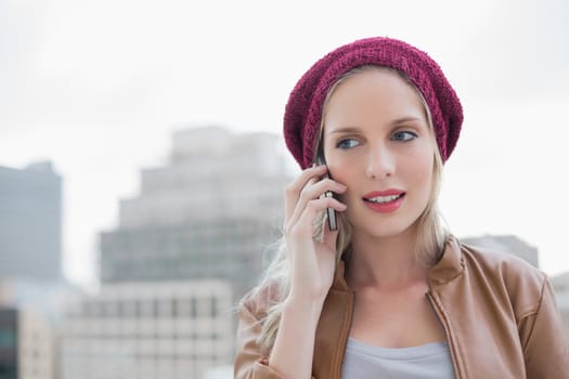 Focused casual blonde on the phone outdoors on urban background
