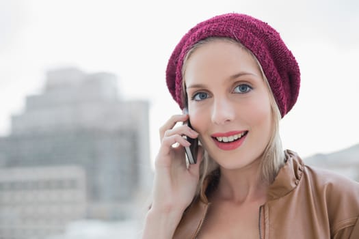 Surprised casual blonde on the phone outdoors on urban background