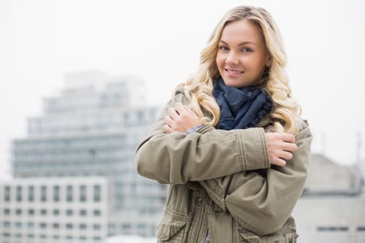Cold trendy blonde posing outdoors on urban background