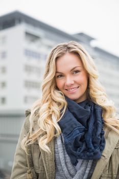 Smiling trendy blonde posing outdoors on urban background
