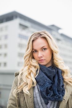 Unsmiling attractive blonde posing outdoors on urban background