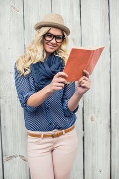 Cheerful fashionable blonde reading outdoors on wooden background