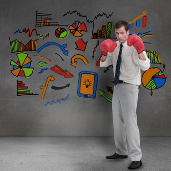 Businessman with boxing gloves standing in front of colored graphics in grey room